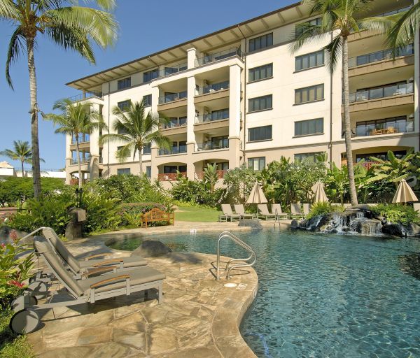 The image shows a luxurious resort with a swimming pool, lounge chairs, palm trees, and a multi-story building in the background.