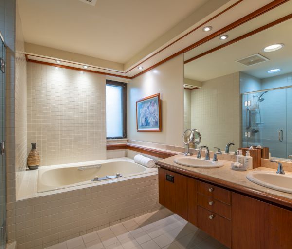 The image shows a modern bathroom with a bathtub, double sinks with mirrors, and a walk-in shower.