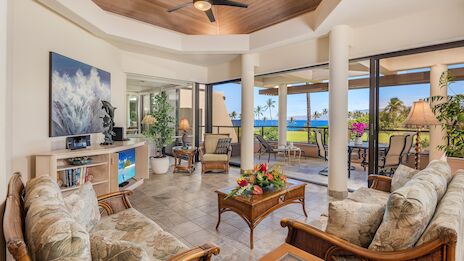 The image showcases a stylish living area with decorative plants, ocean views, and comfortable furniture, creating a relaxing atmosphere.