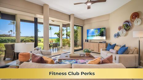 The image shows a modern living area with large windows, tropical views, cozy furniture, and a TV displaying a beach scene.